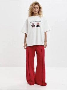 Détail du t-shirt blanc oversize en coton avec imprimé matriochka et pantalon large rouge