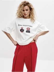 Détail d'un t-shirt oversize en coton blanc avec imprimé poupée russe et pantalon rouge