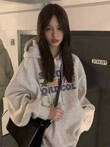 Close-up of oversized light grey hoodie with vintage varsity print and kangaroo pocket