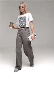 Street style view of white cotton T-shirt with tribal print and wide-leg denim pants
