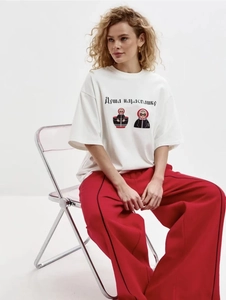 Gros plan sur t-shirt en coton blanc avec motif poupée russe et pantalon large rouge