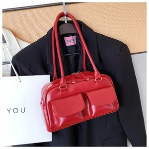 Detail of red patent leather handbag with dual front flap pockets and long top handles