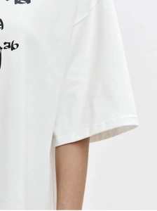 Close-up of white cotton T-shirt with drop shoulder sleeve and black artistic text print