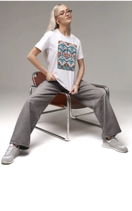 Detail of white cotton T-shirt featuring abstract colorful print on a seated model