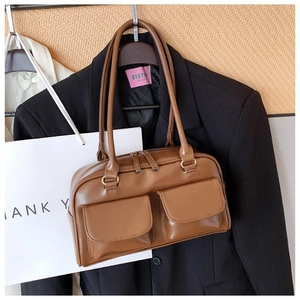 Detail of caramel faux leather bag featuring double straps and vintage flap pockets