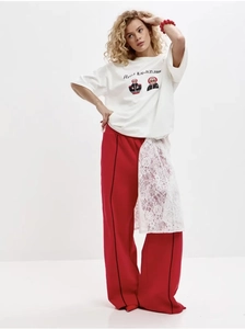 Détail du pantalon large rouge avec patchwork en dentelle blanche et rayures noires