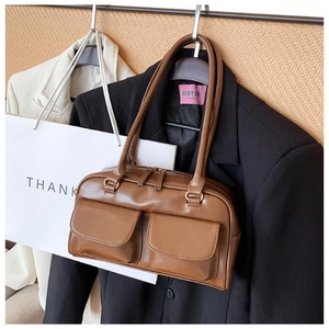 Detail view of brown PU leather handbag featuring dual front flap pockets and gold hardware