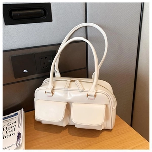 Detailed view of a cream white retro square handbag with front flap pockets on a wooden table