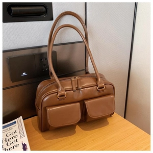 Detail view of brown vintage style handbag with two large front flap pockets and dual zippers