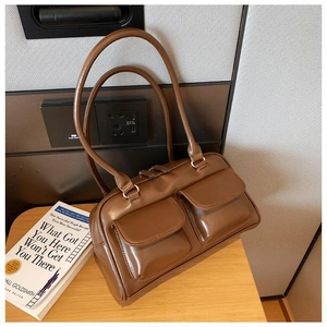 Detail view of a vintage brown handbag with dual front pockets and glossy PU leather texture