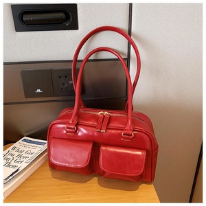 Detail of red glossy leather handbag with double pockets on wooden table