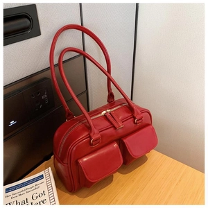 Detail of red PU leather Boston bag featuring dual front flap pockets and long handles