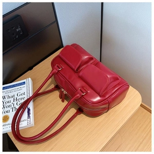 Detail of red faux leather handbag featuring dual front flap pockets and smooth finish