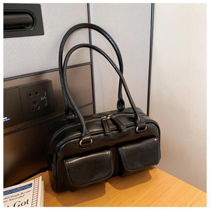 Detail of a vintage black faux leather handbag featuring dual front flap pockets and gold zippers