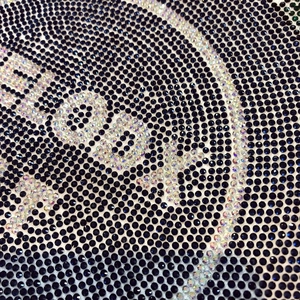 Macro du logo DIOR en strass irisés sur le tissu en coton bleu marine du t-shirt
