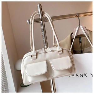 Detail view of cream shoulder bag with dual front flap pockets and zip closure