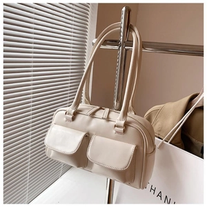 Detail of a creamy white structured handbag with double front pockets and metal zippers