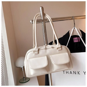 Detail of a creamy white crossbody bag with double front flap pockets on a silver hanger