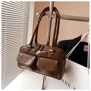 Detailed close-up of brown faux leather tote bag with front pockets on silver hanger