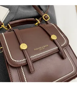Detail of vintage dark brown leather bag with white stitching and gold metal buckle