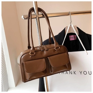 Detail of a brown vintage PU leather handbag with two front pockets and zipper closure