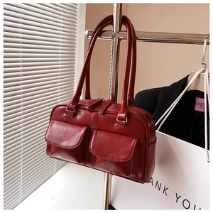 Detail of dark red leather handbag with front pockets and elegant gold hardware