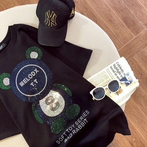 Détail d'un t-shirt noir en coton avec motif ours en strass et lettres brillantes