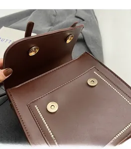 Detail view of brown leather backpack featuring dual magnetic snap closures and contrast stitching