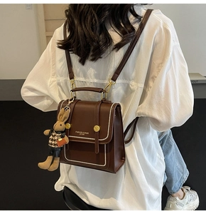 Close-up of brown vintage leather backpack with white stitching and plush rabbit charm