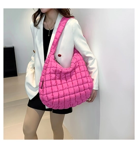 Detail of fuchsia quilted puffer shoulder bag with soft cloud-like padded texture