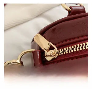 Detail of dark red glossy patent leather bag with premium gold metal zipper hardware