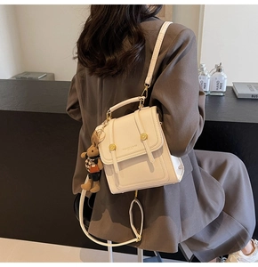 Detail of cream leather backpack with gold hardware and a cute brown bunny charm