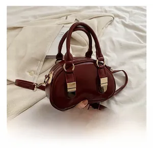 Close-up of wine red Boston bag showing smooth PU leather and gold hardware detail