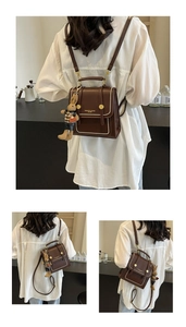 Detail view of vintage dark brown backpack with white stitching and plush bunny charm