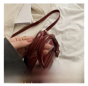 Detail of red glossy leather handbag with solid handle and golden hardware buckle