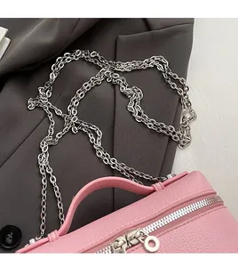 Detail of pink lychee leather handbag featuring silver chain strap and dual zippers