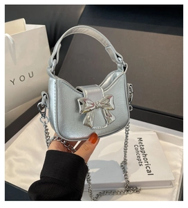 Close-up of a silver mini bow bag with metallic finish and detachable chain strap