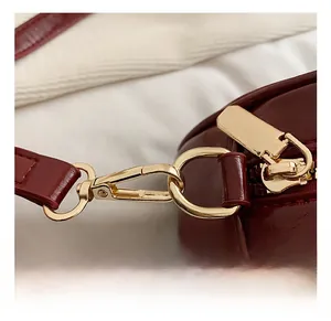 Close-up of premium golden metal hook and zipper on burgundy leather handbag details