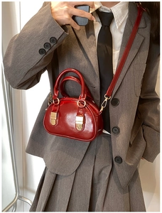 Detail of red patent leather bowling bag with gold hardware and removable strap