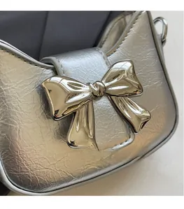 Detail of silver bag featuring a 3D metal bow clasp and pleated metallic leather texture