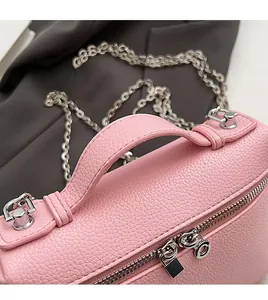 Detail of pink pebbled leather handbag featuring silver chain and round top handle