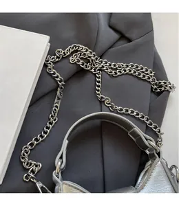 Detail of silver crossbody bag featuring cracked leather texture and metallic chain strap