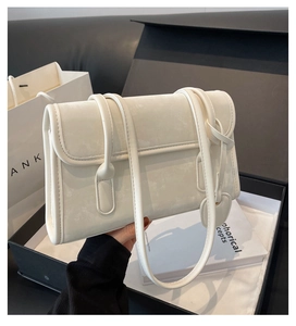 Detail of cream white suede shoulder bag featuring a heart-shaped charm and dual straps
