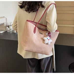 Rear view of a model wearing a large pink tote bag with burgundy leather trim and star charm