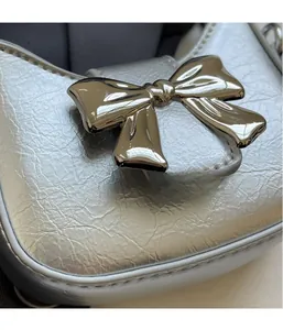 Macro shot of silver bow handbag showing textured metallic leather and hardware details