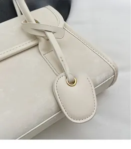 Detail of white leather shoulder bag featuring vintage texture and leather knot accent