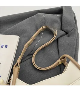 Detail of slim leather strap with golden circular hardware on a chic bucket bag