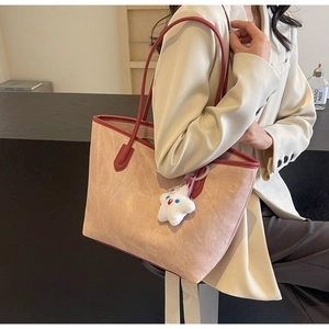 Detail of beige tote bag with burgundy leather trim and cute star plush pendant