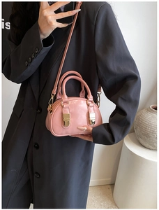 Pink patent leather mini crossbody bowling bag shown in a lifestyle model shot