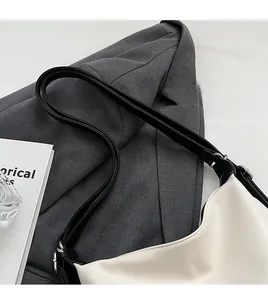 Détail d'une bandoulière noire réglable avec boucle en métal sur un sac monochrome